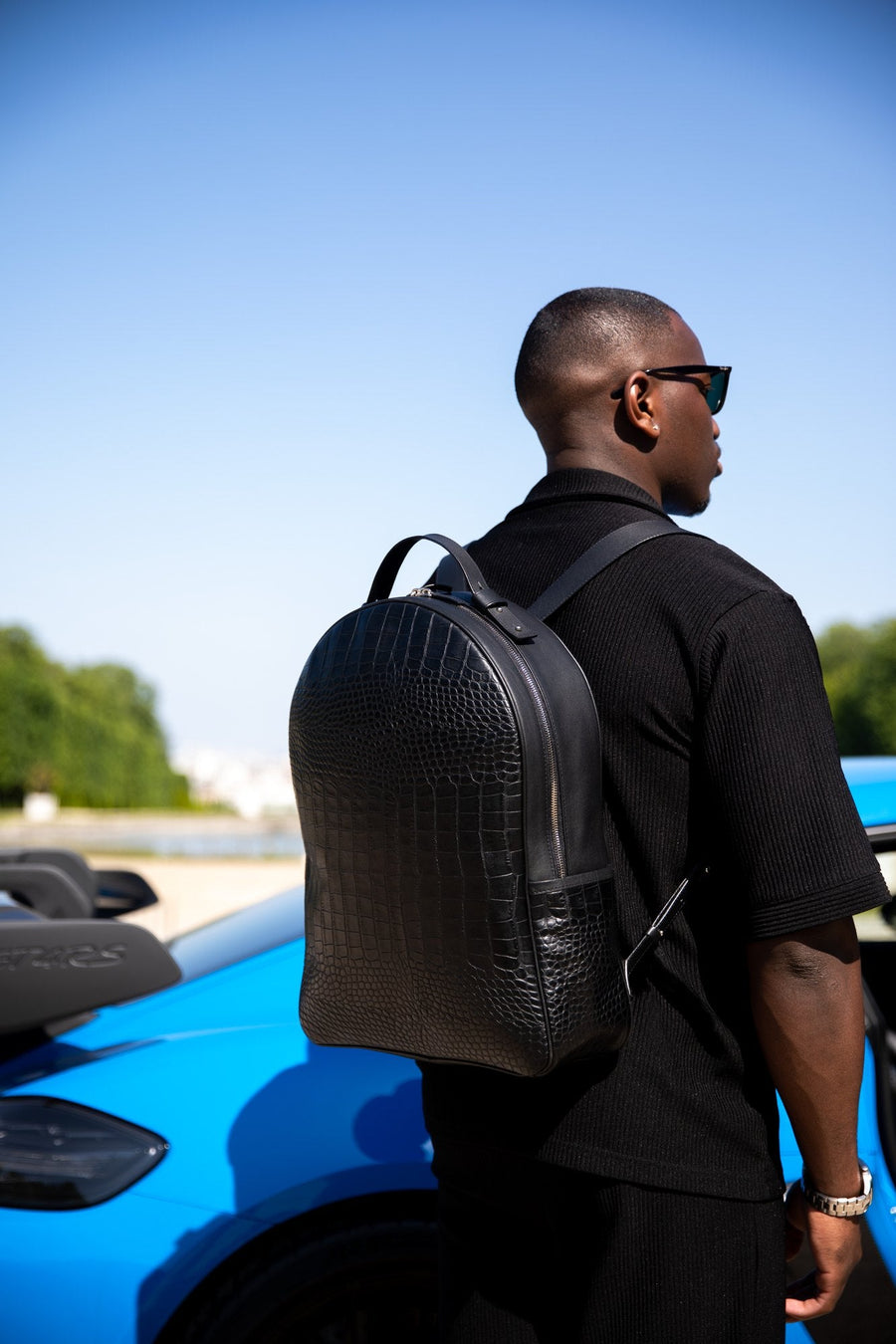 Sac à dos en cuir noir embossé façon croco, porté sur le dos
