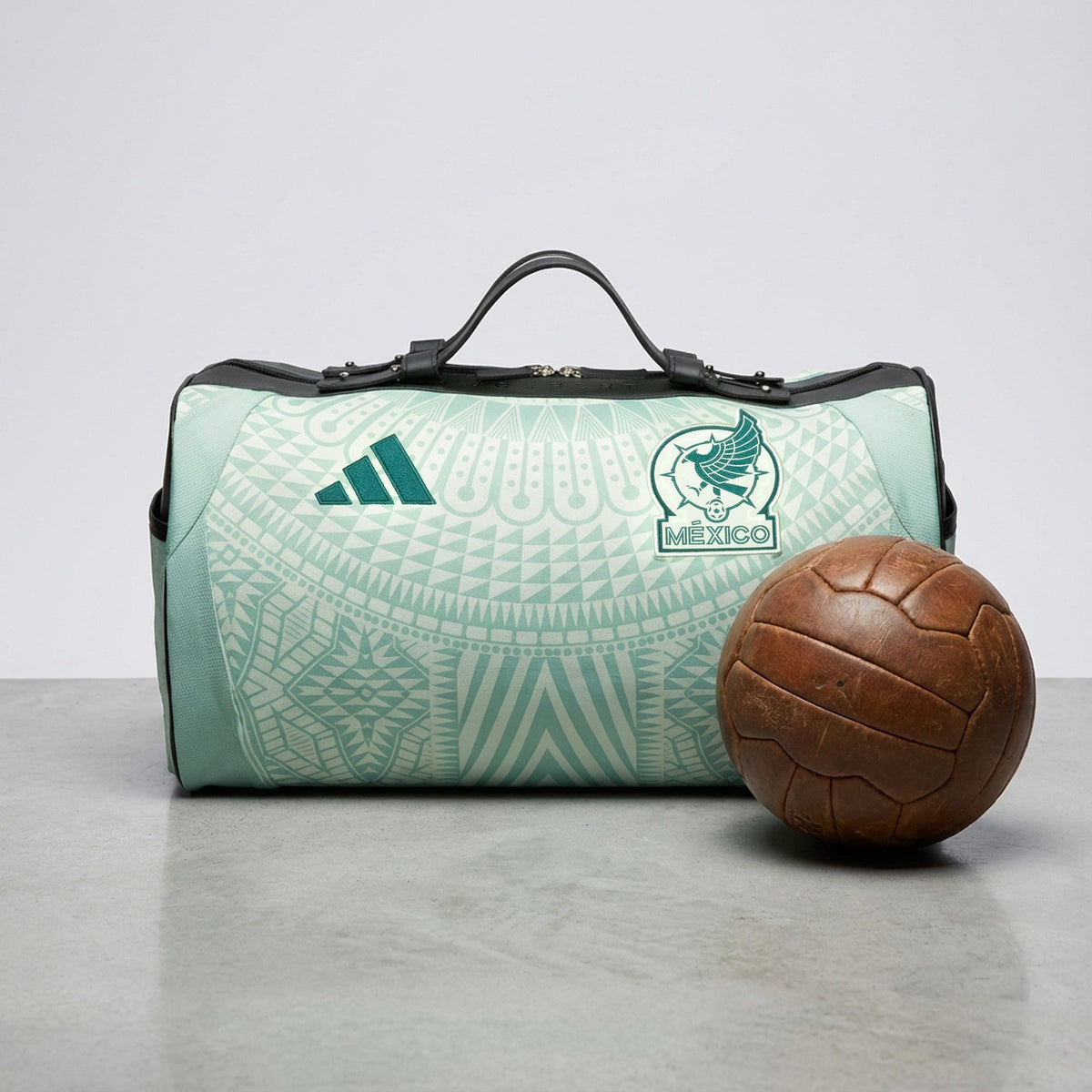 Sac en maillot vert d'eau du Mexique, logo adidas et écusson MÉXICO, à côté d'un ballon de cuir ancien