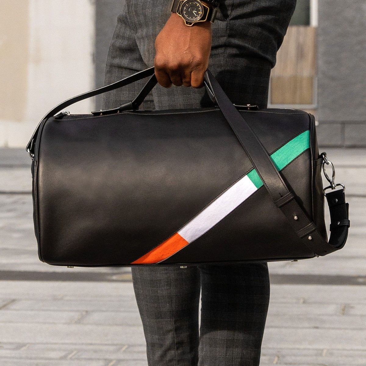 Sac en cuir noir traversé en diagonale par une bande orange, blanc et vert, aux couleurs de la Côte d'Ivoire