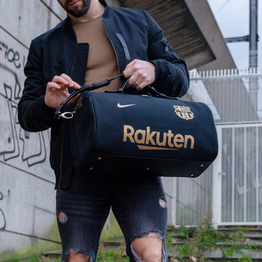Sac JOUBERT en maillot noir et or du FC Barcelone, écusson et Rakuten dorés, tenu à deux mains