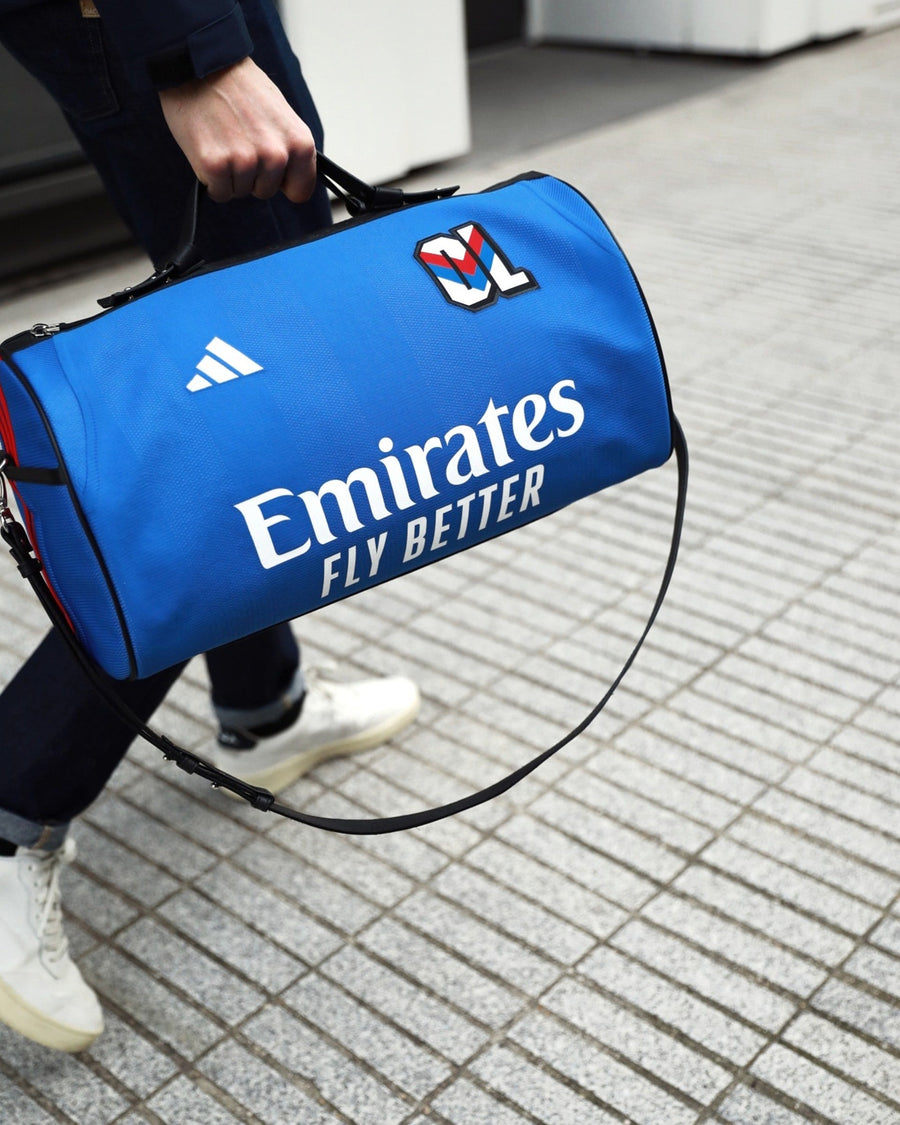 Sac taillé dans le maillot extérieur bleu de l'Olympique lyonnais 2024/25, adidas et Emirates, porté à la main