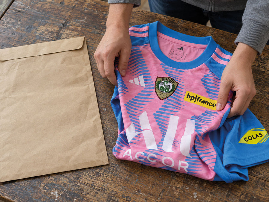 Un maillot plié, intact, posé sur la table de l’atelier à côté de l’enveloppe d’envoi