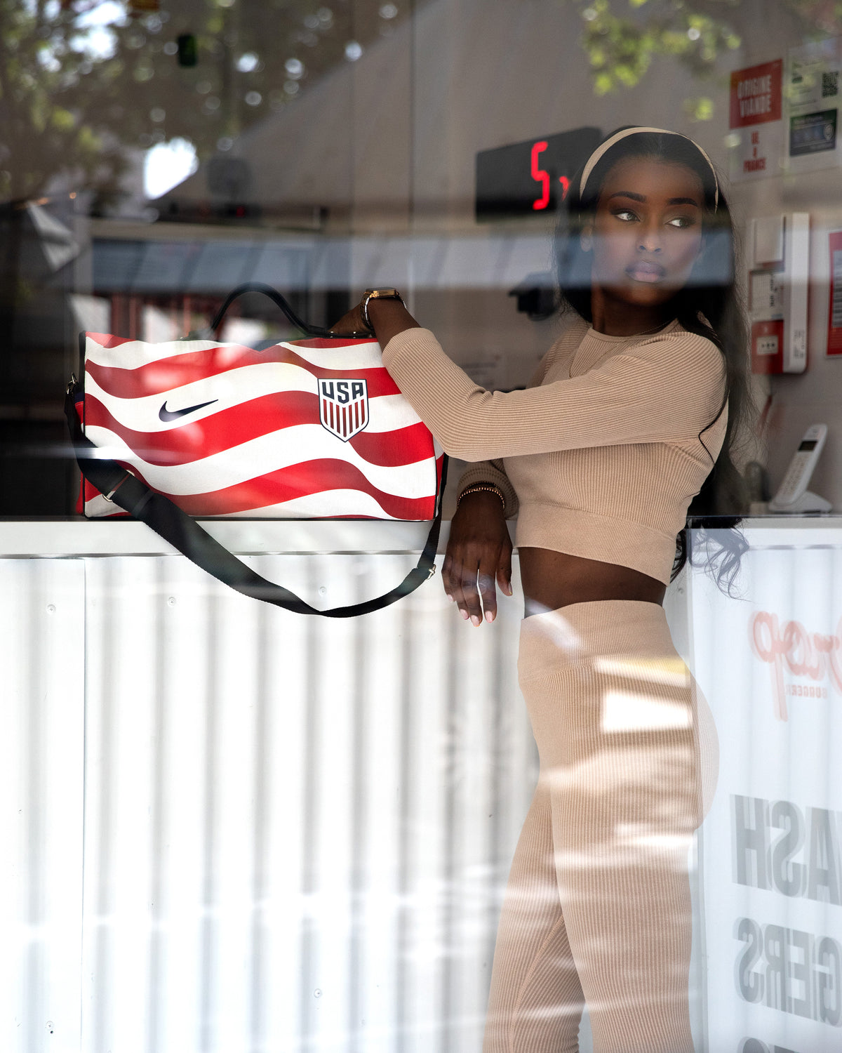 Sac 45 Métamorphose en maillot des États-Unis, rayures rouges et blanches, porté à l'épaule derrière une vitrine