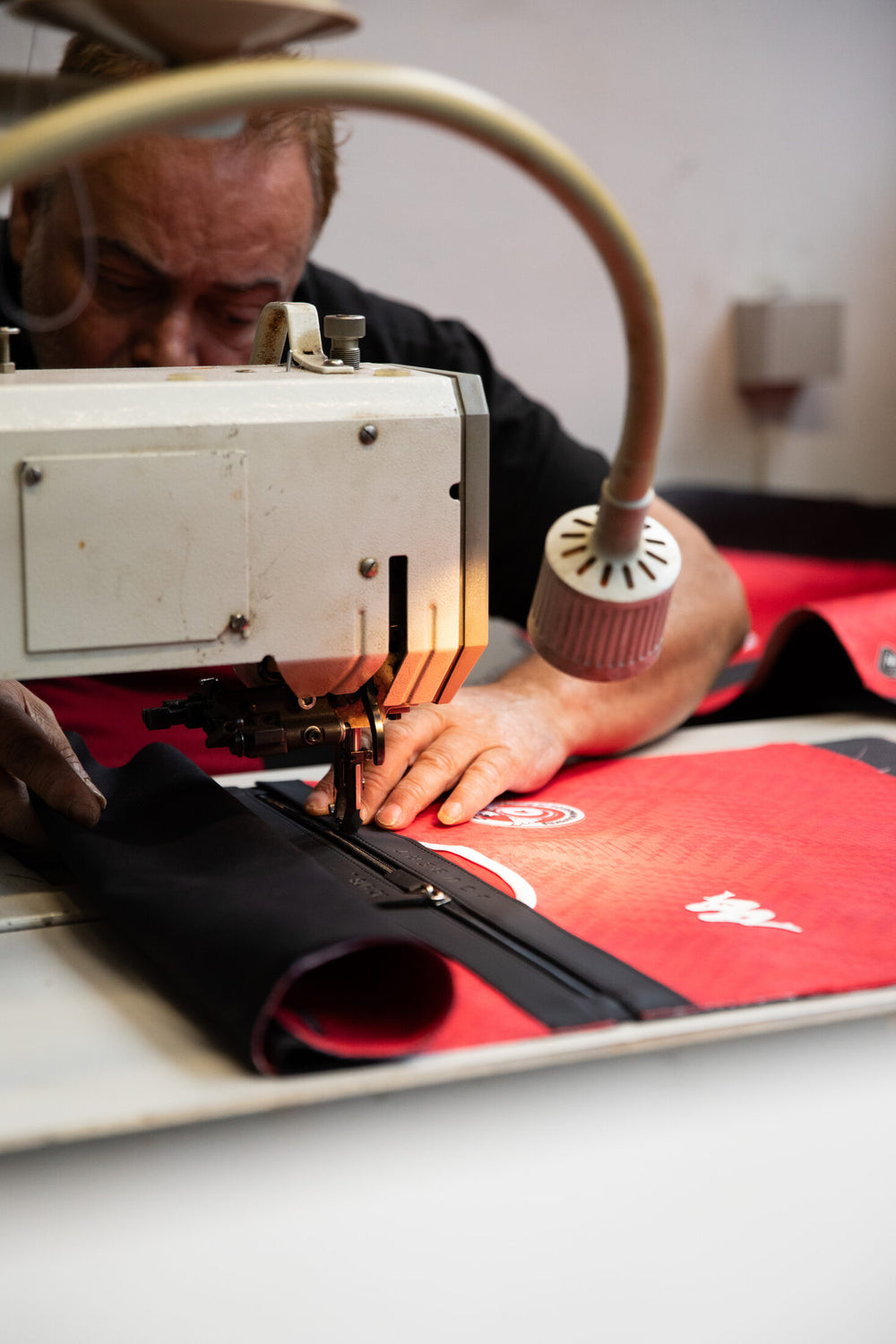 The JOUBERT workshop: a craftsman machine-stitches the red jersey of a future Métamorphose bag.