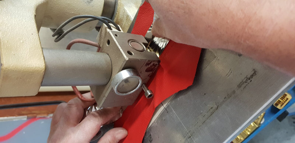 The JOUBERT workshop: the press hot-stamps the logo into a red hide.