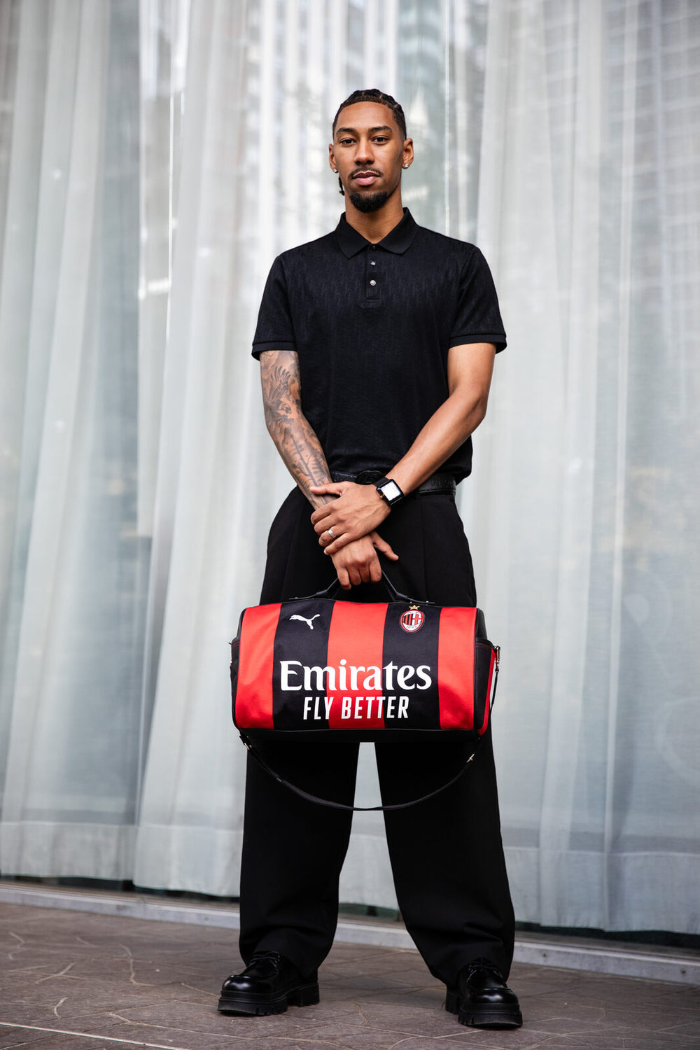 Red and black Métamorphose bag in an AC Milan jersey, carried at Beaugrenelle.